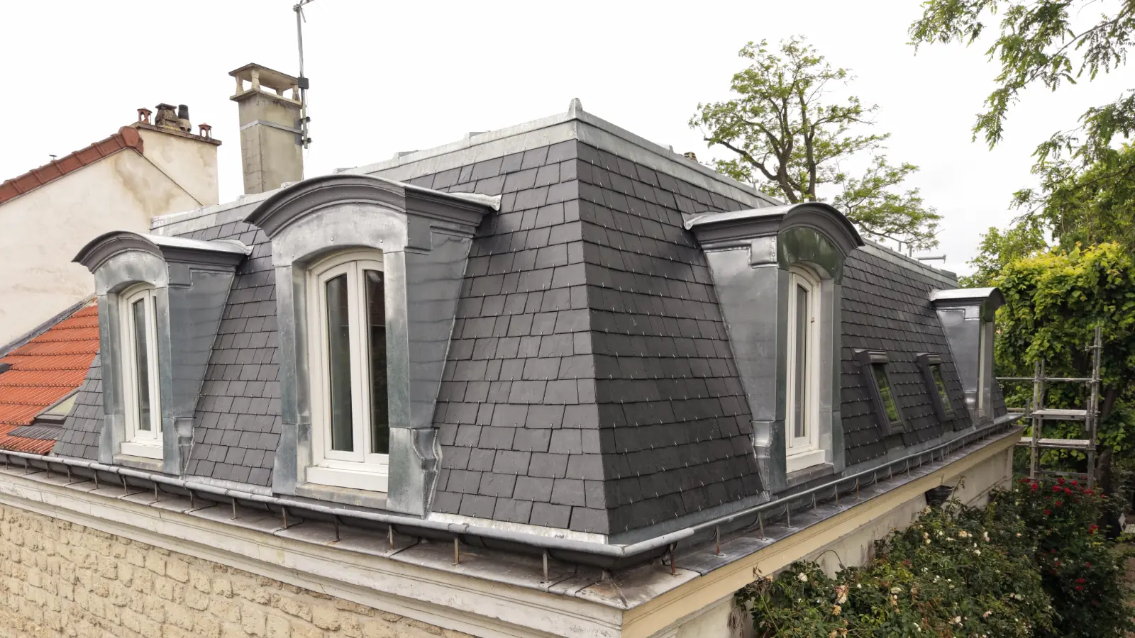 Toiture réalisée en ardoise avec deux lucarnes et des finitions en zinc